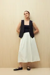 Falda midi color blanco con estampado de lunares negros.