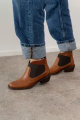 Botín de cuero color marrón con elásticos laterales negros y taco bajo.