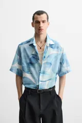 Camisa verde agua con estampado abstracto, corte relaxed fit, cuello solapa, manga corta y cierre frontal con botones.
