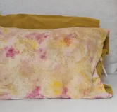 Almohadón rectangular de seda cruda teñida artesanalmente con té, flores, hojas, cortezas e insectos. El reverso es de chenille color mostaza.