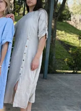Vestido midi color beige de lino con corte recto, mangas cortas y cierre frontal con botones.