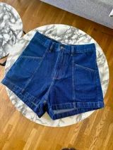 Short de jean azul oscuro, de tiro alto, corte semi baggy y ruedo desflecado.