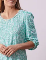 Blusa estampada color beige con cuello redondo calado y mangas 3/4 abullonadas con terminación elastizada.