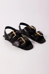 Sandalias negras de cuero con dos tiras anchas sobre el empeine, hebillas doradas y tira trasera.