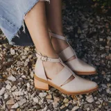 Zapato de cuero negro con detalle de charol, taco de madera con folia en cuero de 5cm, cierre YKK en talón, hebilla y elástico en el empeine.