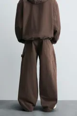 Pantalón negro de corte amplio, confeccionado en tejido de algodón con efecto lavado. Presenta bolsillos frontales, traseros de parche, tira multifunción y bolsillos laterales en las perneras. Cuenta con cierre frontal con cremallera y botón.