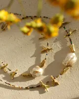 Collar corto con cuentas de piedra natural multicolor, perlas de río irregulares y dijes de bronce con forma de coral.