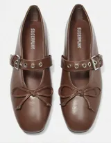 Balerinas color marrón con correa sobre el empeine con hebilla metálica y detalle de moño en la punta.