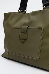 Bolso blanco de símil cuero con terminación suave. Tiene asas anchas de cinta negra y un bolsillo frontal con solapa.