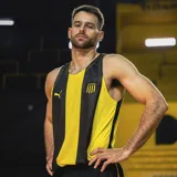Musculosa de básquet Puma del Club Atlético Peñarol, modelo Home 2025. Diseño a rayas verticales amarillas y negras con logo de Puma y escudo del club.