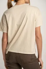 Remera color arena de algodón peinado con estampa frontal de texto con diseño floral.