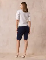 Cárdigan tejido color blanco, marca Tahari. Escote en V, manga corta abullonada con puño y abertura central con botones.
