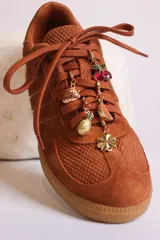 Zapatillas bajas de gamuza celeste con cordones y pañuelos estampados atados a los cordones.