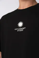Remera oversize de algodón premium color negro, con estampado frontal minimalista de un sol y la frase "VCP CONCEPT STUDIO" en blanco.