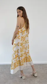 Vestido largo de seda estampada con flores amarillas sobre fondo blanco, corte halter.