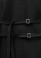 Chaleco negro largo con cuello halter, espalda abierta y cierre ajustable en la parte posterior.