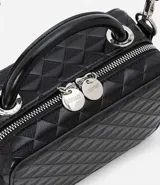 Bolso transversal tipo camera bag, color negro, hecho en material sintético texturizado. Tiene correa fina ajustable y removible, cierre por cremallera y colgante pompón.