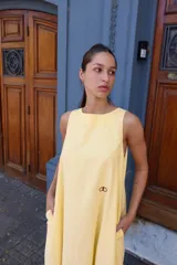 Vestido largo gris sin mangas, con escote redondo, bolsillos laterales y logo bordado en el frente.