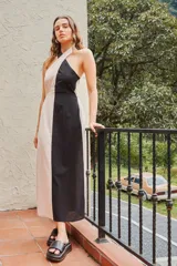 Vestido midi sin mangas, color block en blanco y negro, con cuello halter y corte entallado. Presenta detalle de punto smock y elástico en la cintura.