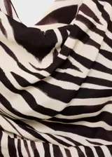 Blusa sin mangas con estampado de cebra en tonos marrón y beige. Presenta cuello asimétrico, diseño drapeado y corte entallado.