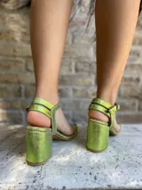 Sandalias de cuero color dorado, con taco cuadrado y tira delgada en el tobillo.