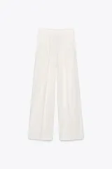 Pantalón blanco de tiro medio con pinzas delanteras y raya planchada. Confeccionado en hilatura con mezcla de algodón. Presenta bolsillos laterales, trabillas en la cintura y cierre frontal con cremallera, botón y gancho metálico.