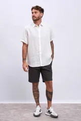 Camisa blanca de lino de manga corta con cuello clásico y cierre con botones. Corte recto.