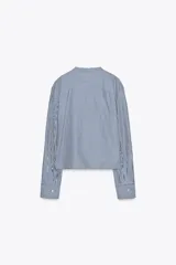 Camisa de manga larga con cuello mao y cierre frontal con botones ocultos. Diseño a rayas verticales azules y blancas.