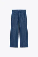 Pantalón de jean azul con cintura elástica ajustable con cordones, tiro medio y bolsillos de parche en la parte trasera.