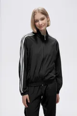 Campera deportiva negra con cierre frontal, cuello alto y tres rayas blancas en los hombros y mangas.