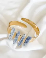 Brazalete rígido dorado con cuatro incrustaciones de piedra cianita azul.