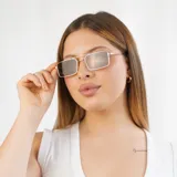 Lentes de sol rectangulares con marco dorado y lentes negros.