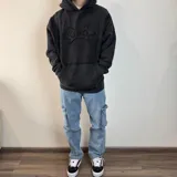 Canguro negro con capucha, corte oversize y estampa abstracta en el pecho.