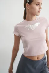 Remera corta de algodón color rosa con cuello redondo y estampado plateado en el frente.
