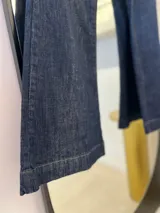 Pantalón de jean Oxford de tiro alto, color azul oscuro. Tiene dos bolsillos redondeados en la cadera y dos bolsillos en la parte trasera. Cierre con botón metálico y cremallera.