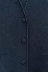 Chaqueta azul marino de punto con cuello redondo y escote pico, manga larga, bajo peplum y cierre frontal con botones forrados.