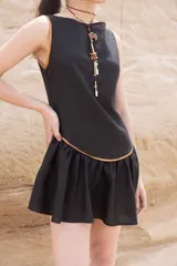 Vestido corto negro con detalles en color camel, sin mangas y falda con volados.