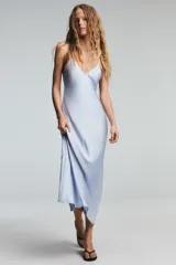 Vestido midi negro de tejido satinado, con escote en pico y tirantes finos ajustables. Presenta un detalle de tiras cruzadas en la espalda descubierta y cierre con cremallera metálica.