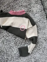 Buzo de hilo en color verde y crudo con cuello rosa y bordado de carita a mano.