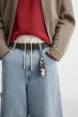 Llavero de piel con estampado animal en blanco y marrón, con detalle de costuras laterales y mosquetón metálico plateado.