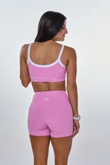 Conjunto deportivo rosa compuesto por un top con tirantes blancos y un short ajustado con costuras blancas.