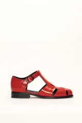 Sandalia roja de cuero vacuno con diseño de tiras entrecruzadas y hebilla lateral. Tiene suela de cuero artesanal y taco bajo.