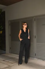 Conjunto de chaleco y pantalón negro con finas rayas verticales blancas. El chaleco es entallado, con escote en V y cierre frontal con botones. El pantalón es de corte palazzo.