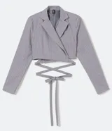 Blazer cropped gris con estampado de rayas verticales, cuello solapa, cierre cruzado y lazo en la espalda.