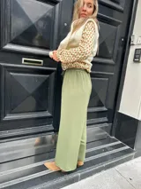 Pantalón verde de seda opaca, corte ancho y fluido, tiro medio alto y elástico en la cintura.