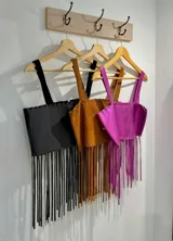 Top corto con breteles finos y flecos en el ruedo, confeccionado en cuero sintético.