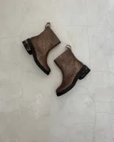 Botín marrón de cuero vacuno, con caña media, cierre lateral y suela de goma.