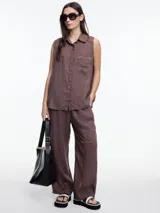 Pantalón negro de lino con elástico en la cintura y calce relajado. Incluye bolsillos laterales y un bolsillo invertido. Detalles de bordado tipo pespunte en color gris recorren la pierna y el bajo.