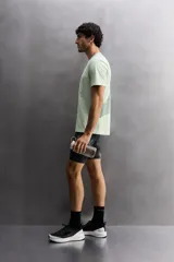 Camiseta deportiva verde claro confeccionada en tejido técnico, ligero y elástico en cuatro direcciones. Tiene cuello redondo, manga corta, zonas con estructura perforada y logo estampado.