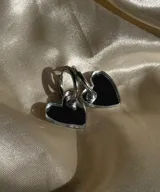 Aros colgantes con forma de corazón, hechos de acrílico negro y con cierre de aro plateado.